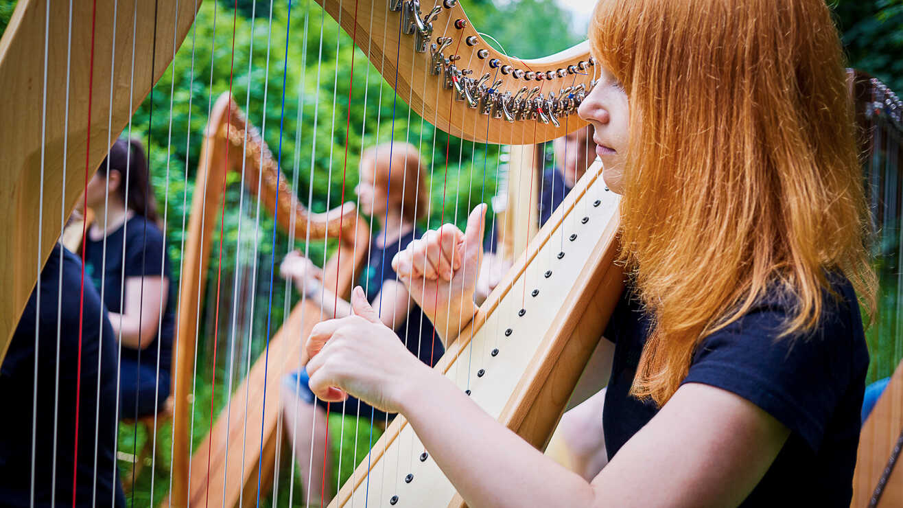 Damer spiller harpe på et arrangement hos Voksenåsen